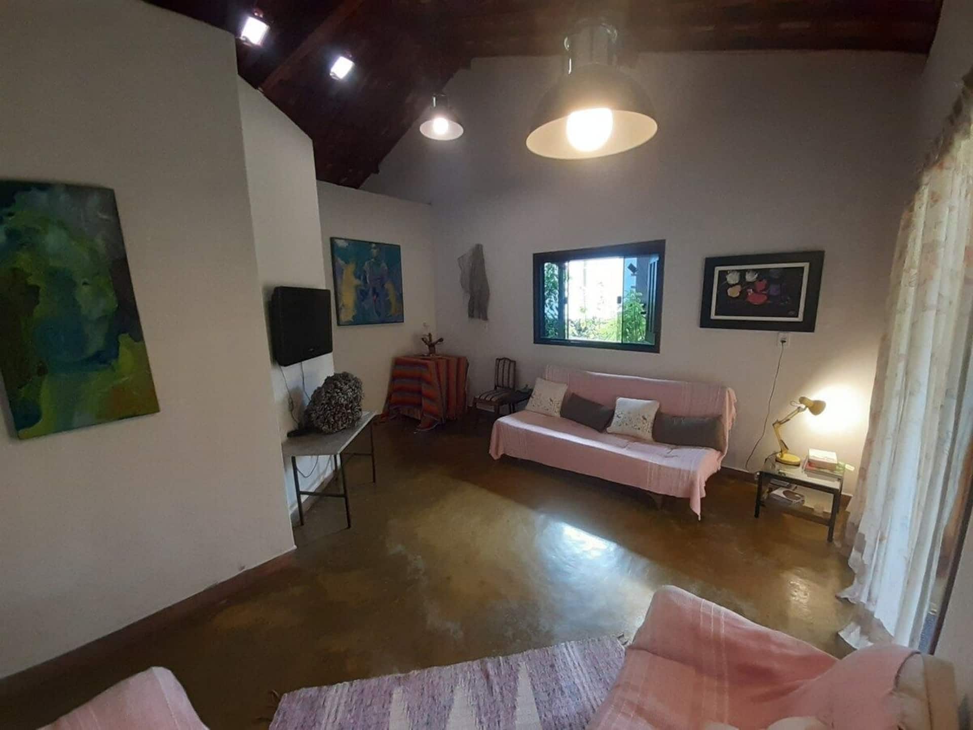 Sala de estar com sofá, telas originais e piso de cimento queimado