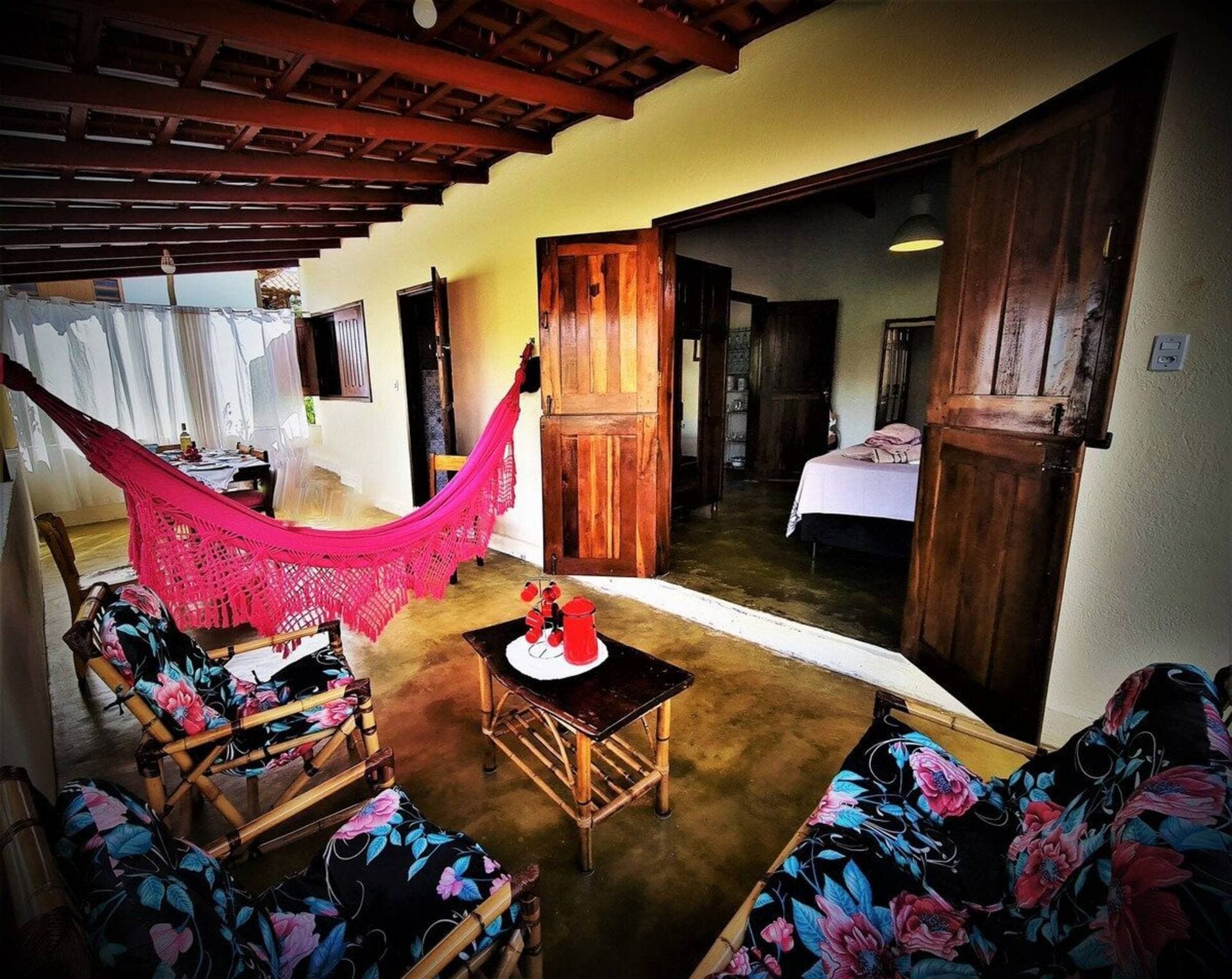 Sala integrada à varanda, com rede rosa