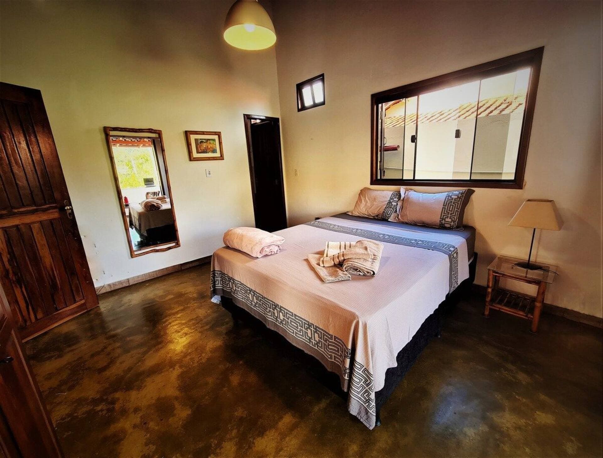 Suíte da Casa da Artista, com cama de casal entre duas janelas