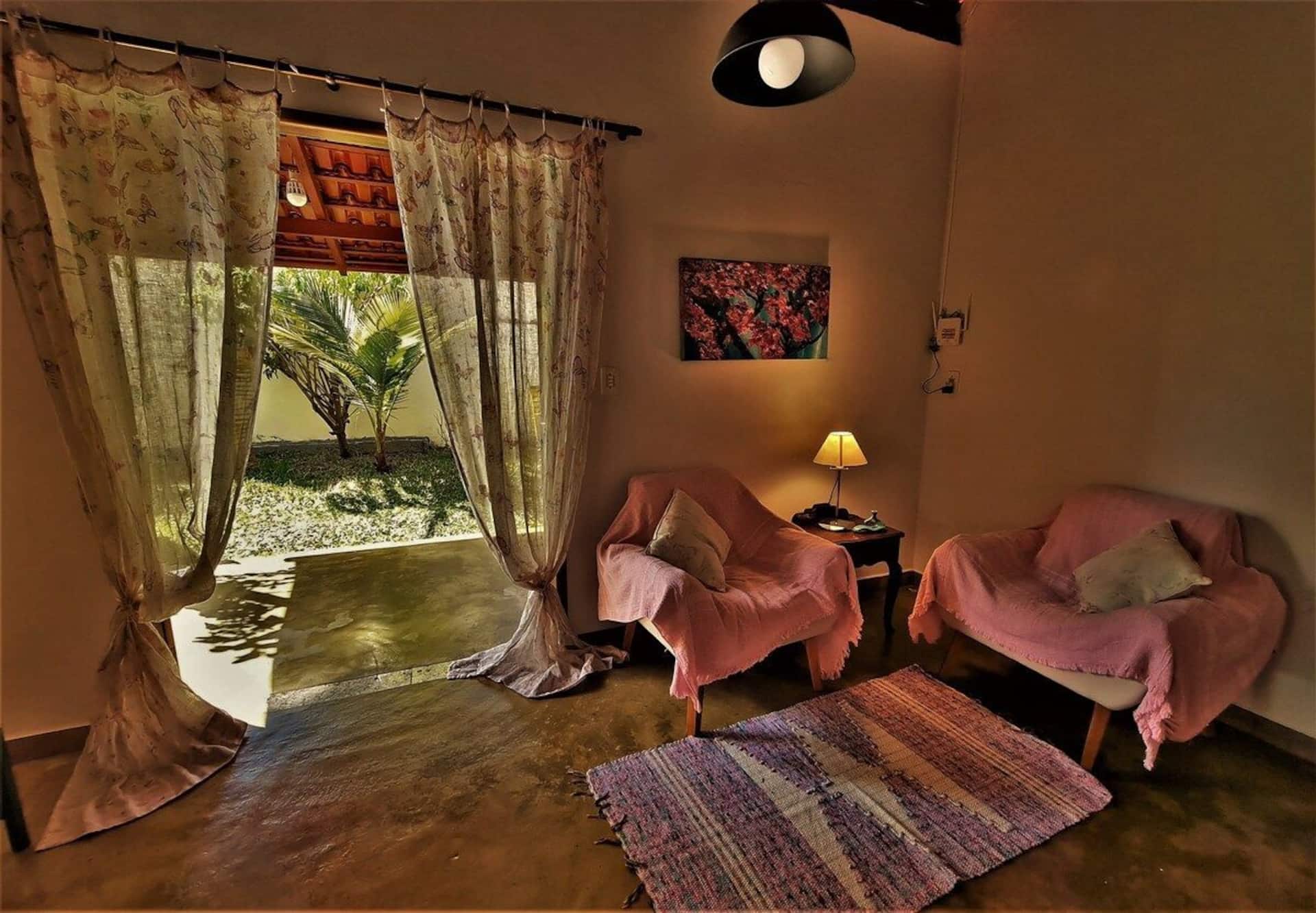 Sala de estar com poltronas rosa e cortinas leves